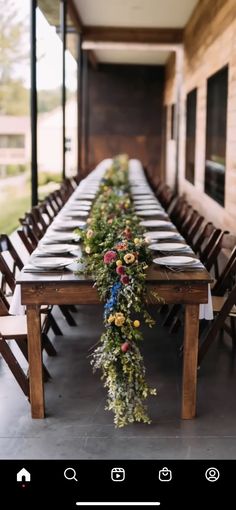 a long table with flowers and greenery is set up for an outdoor dinner party