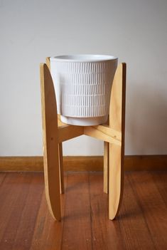 a white bucket sitting on top of a wooden chair next to a wall and hardwood floor