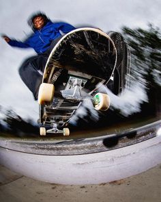 a man riding a skateboard up the side of a metal rail with trees in the background