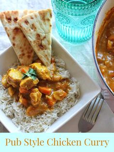 a bowl of chicken curry next to a plate of rice and pita bread on a table