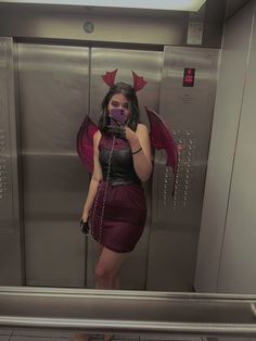 a woman taking a selfie in front of an elevator with wings on her head