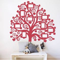 a red tree with hearts and frames on the branches is in front of a white wall