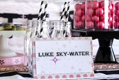 a table topped with mason jars filled with drinks and candy bar signs that read luke sky - water