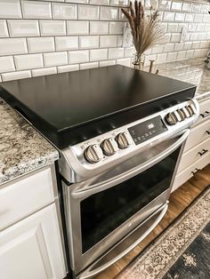 a stove top oven sitting inside of a kitchen next to white cabinets and counter tops