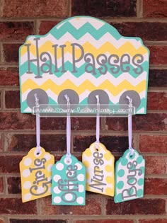 three tags hang on a brick wall with the word hall passes written in white and blue