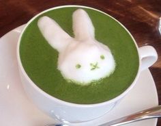 a cup filled with green liquid and a white bunny face in the foam on top