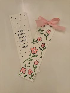 two bookmarks with pink flowers and stars on them, one has a ribbon tied around it