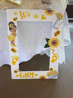 a white frame with sunflowers and a baby's footprints on it that says, it is a girl