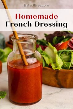 homemade french dressing in a glass jar with a wooden spoon and salad in the background