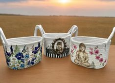 three baskets with buddha images on them sitting on a table in front of the sun