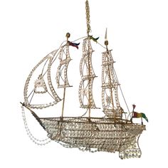 a boat made out of glass beads on a white background with the sails turned down