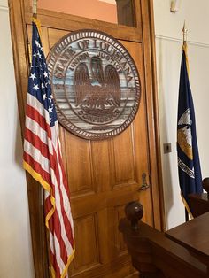 an american flag and two flags in front of a wooden door with the seal of the united states on it