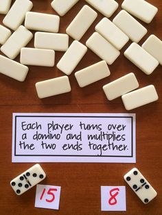 dices and numbers on a table with a sign that says each player turns over a domino and multiplies the two ends together