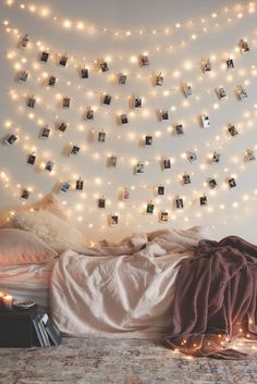 a bedroom with lights strung from the ceiling and pictures on the wall above the bed