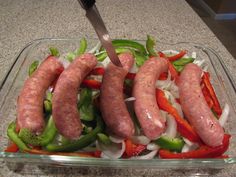 sausages and peppers in a glass dish with a knife