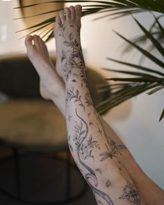 a person with tattoos on their arm and foot sitting next to a potted plant