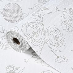 a white wallpaper with roses on it and a roll of paper next to it