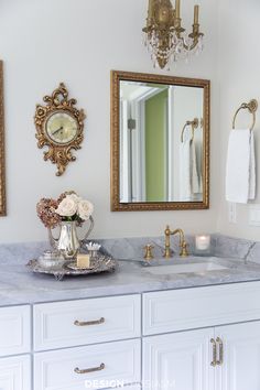 a bathroom with marble counter tops and gold framed mirrors on the wall above it is decorated with flowers