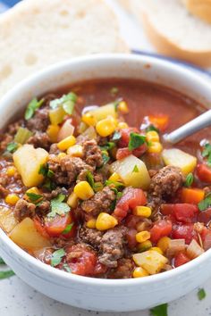 a white bowl filled with meat and vegetables next to some slices of bread on a plate