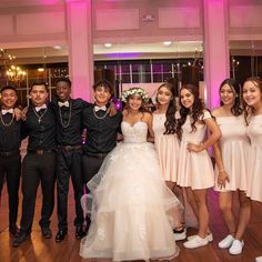 a group of people standing next to each other in front of a pink lit room