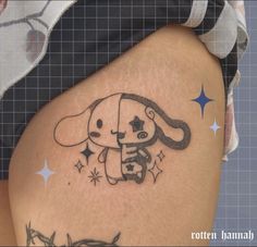 a woman's thigh with a tattoo of a dog holding a star on it