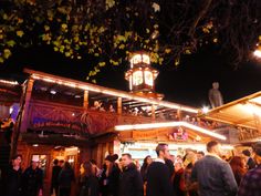 a crowd of people standing in front of a building with lights on it at night