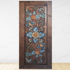 an ornate wooden panel with blue flowers and leaves inlayed to the side, on a wood floor