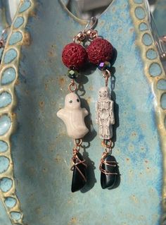 two charms are hanging from a blue bowl with red beads on it and one has a small white bird in the middle