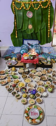 the food is laid out on the floor in front of the wall and decorated with garlands