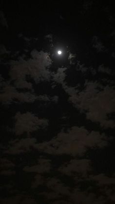 the moon is shining brightly in the dark night sky with fluffy clouds and bright lights