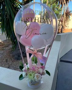 a bunch of balloons that are sitting in a vase with some flowers on the side