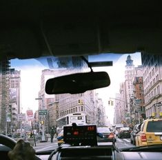 the view from inside a car looking at traffic on a busy city street with tall buildings