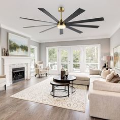 a living room with couches, chairs and a ceiling fan in the middle of it