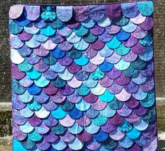 a purple and blue quilt with lots of fish scales on it