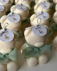 some white chocolates with green bows and tags on them are arranged in the shape of an egg