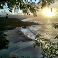 the sun is setting over an ocean with waves coming in from the water and trees