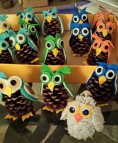 pine cones decorated with owls and pine cones are sitting in a tray on the table