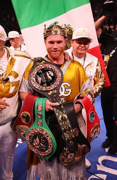 two men are holding up their belts in front of an italian flag and some fans