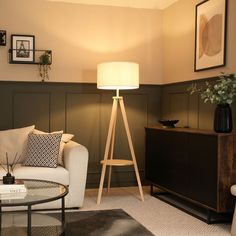 a living room filled with furniture and a lamp on top of a wooden stand next to a white couch