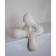 a white sculpture sitting on top of a table next to a white wall and floor