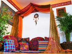 a bed covered in lots of pillows next to a potted plant