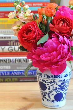 there is a vase with flowers in it sitting on the table next to some books