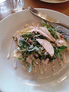 a white plate topped with lots of food on top of a wooden table next to utensils