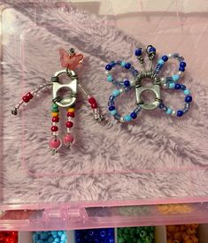 two pairs of earrings are sitting in a plastic box with beaded beads on it