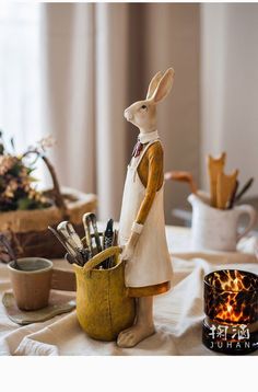 a white rabbit figurine sitting on top of a table next to a cup filled with pens and pencils