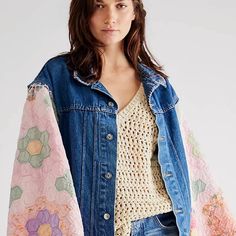 a woman wearing a jean jacket with floral designs on the sleeves and shoulders, standing in front of a white background