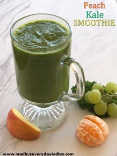 a green smoothie in a glass mug next to some fruit