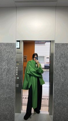 a woman is standing in an elevator talking on her cell phone while wearing a green shawl