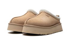 The Women’s UGG Tazz “Sand” is the women’s sizing of the slip-on moccasin with a platform style sole in a neutral colorway.  The Ugg Tazz Slipper is made for indoor or outwear wear, and features a warm inner lining constructed of plush sheepskin and upcycled wool.  The upper has a Sand-colored suede construction with an embroidered braid around the collar.  Uggs branding is seen on the lateral side.  The platform-style sole gives the wearer a significant boost in height, and is constructed in soft yet durable EVA foam for all-day comfort. Tazz Suede Platform Slippers, Shoes Ughs, Tazz Slipper Ugg, Tazz Slipper, Brian Smith, Mid Jordan 1, Ugg Tazz, Ugg Ultra Mini, Nike X Travis Scott