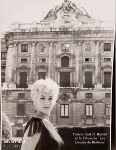 a black and white photo of a woman in front of a building